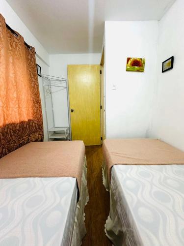 a room with two beds and a yellow door at Host Homes Camella Whole House- 3BR Cozy Townhouse in Campetic Palo in Palo