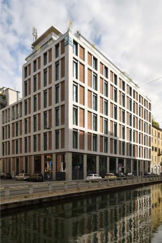 a large building next to a river at 21 House of Stories Navigli in Milan