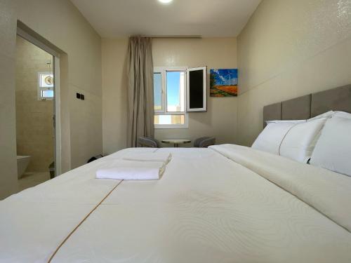 a bedroom with a large white bed and a bathroom at Sea Turtles Guest House #2 Ras Al Hadd in Al Ḩadd