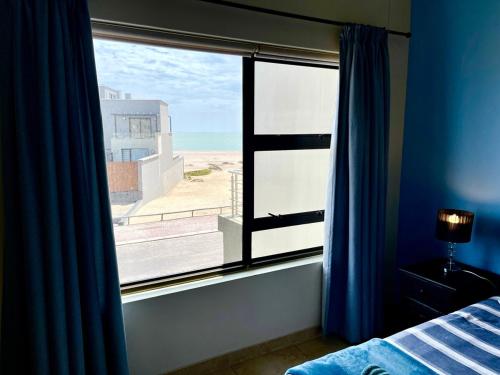 a bedroom with a window with a view of the beach at Family Beach House Retreat in Swakopmund