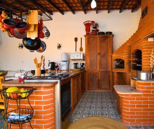 a kitchen with a stove and a brick wall at Casa aconchegante na praia in Peruíbe