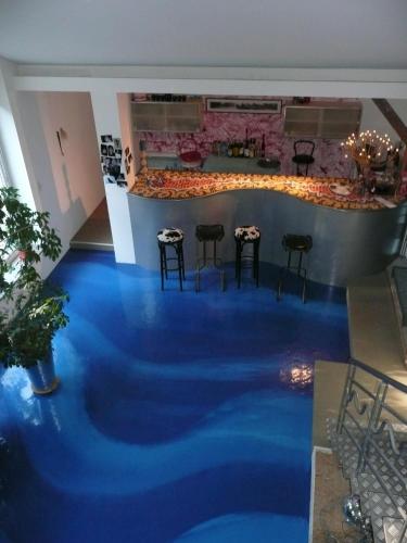 Cette chambre dispose d'un sol bleu avec des tabourets et un bar. dans l'établissement Au Palton, à Raon-aux-Bois