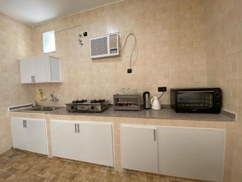 a kitchen with a microwave and a sink at Sea Turtles Guest House #2 Ras Al Hadd in Al Ḩadd