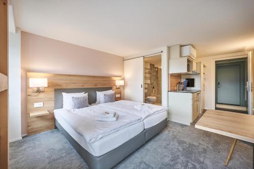 a bedroom with a large white bed and a kitchen at Aparthotel Krone - Self Check-In in Interlaken