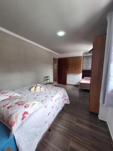 a bedroom with a bed with a floweridered comforter at Pousada Recanto Barão de Biguaçu in Biguaçu