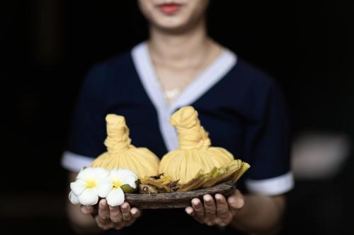 a person holding a plate of food with flowers on it at Pavillon Indochine Boutique - Hotel in Siem Reap