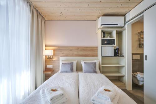 a bedroom with a large white bed with two towels at Aparthotel Krone - Self Check-In in Interlaken