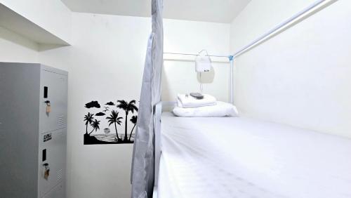 una camera da letto bianca con palme sul muro di Mari Condo Hostel a Manila