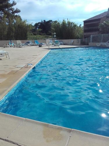 une grande piscine bleue avec des chaises et des chaises dans l'établissement 2-Room Pool, Beach and Harbor, au Pradet