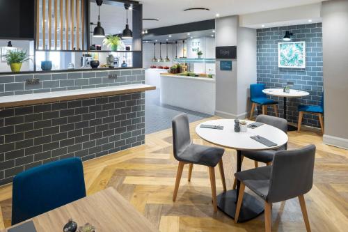 a restaurant with tables and chairs and a kitchen at Holiday Inn London-Bexley by IHG in Bexley