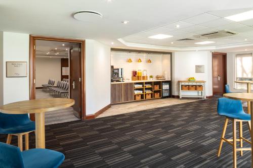 a waiting room with tables and blue chairs at Holiday Inn London-Bexley by IHG in Bexley