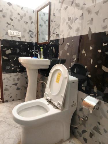 a bathroom with a toilet and a sink and a mirror at Nileshwar Home Stay in Bāgeshwar