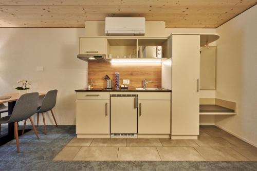 a kitchen with white cabinets and a table at Aparthotel Krone - Self Check-In in Interlaken