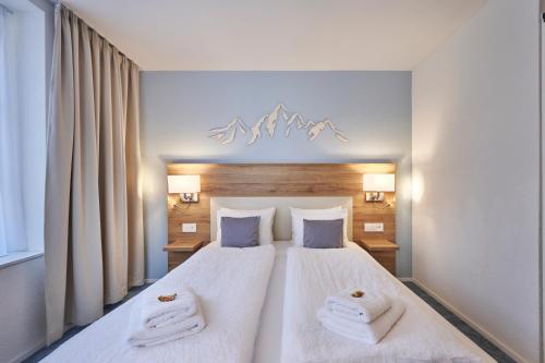 a bedroom with a large white bed with towels on it at Aparthotel Krone - Self Check-In in Interlaken