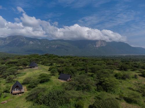 an aerial view of two huts in a field with mountains at Shamba Pori Lodge in Idulo