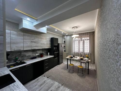 a kitchen with black cabinets and a table with stools at Spacious apartments in the center of Dushanbe in Isfisor