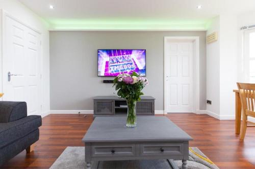 a living room with a vase of flowers on a coffee table at Super Prime Park View Duloch By Tba in Dunfermline