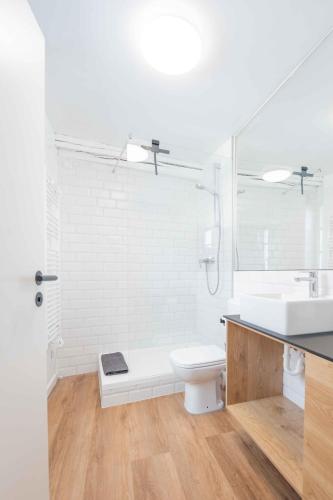a white bathroom with a toilet and a sink at FREYZEIT Apartments Speyer in Speyer