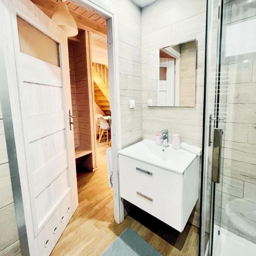 a bathroom with a white sink and a glass door at TuNaChill domki nad morzem w Dziwnowie in Dziwnów