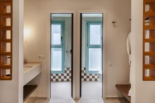 a bathroom with three glass doors and a toilet at Minnŏ Boutique Hotel & Spa in Skopelos Town
