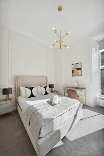 a white bedroom with a large bed and a chandelier at (G1) Elegant 2 bed Blythswood Apartment in Glasgow