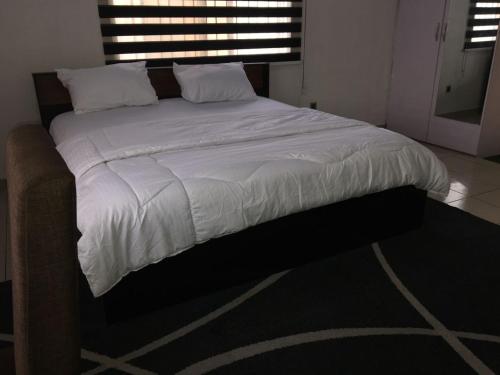 a bed with white sheets and pillows in a bedroom at SLA shortlets in Aguda