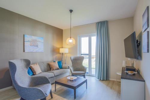 a living room with a couch and chairs and a tv at Boddenluemmel in der Seefahrtschule in Wustrow