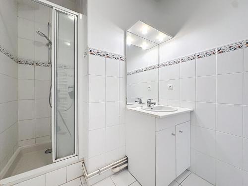 une salle de bain blanche avec un lavabo et une douche dans l'établissement Saint Georges - duplex face mer, à Wimereux