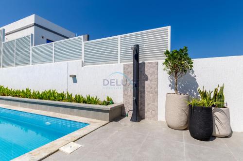 a swimming pool in front of a building at Pool and Sea Views 3BR and Assistant's Room Villa with Beach Access and BBQ Facilities, Sharm - Al Dana Villa, Al Dana Island by Deluxe Holiday Homes in Fujairah