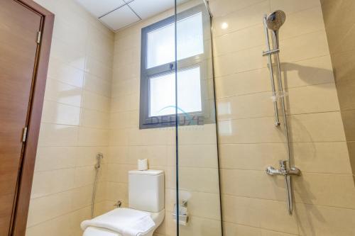 a bathroom with a shower and a toilet and a window at Pool and Sea Views 3BR and Assistant's Room Villa with Beach Access and BBQ Facilities, Sharm - Al Dana Villa, Al Dana Island by Deluxe Holiday Homes in Fujairah