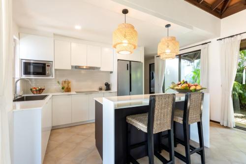 a kitchen with white cabinets and a black island with chairs at Bacaya Beachfront Villa in Bang Rak Beach