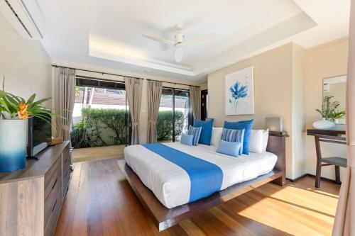 a bedroom with a large bed and a flat screen tv at Bacaya Beachfront Villa in Bang Rak Beach