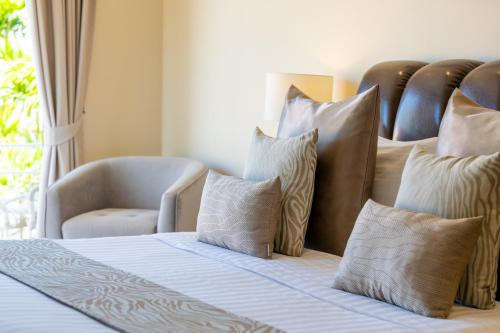 a bedroom with a bed with pillows and a chair at Bacaya Beachfront Villa in Bang Rak Beach