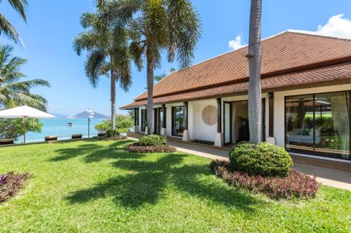 a house with palm trees and the ocean in the background at Bacaya Beachfront Villa in Bang Rak Beach