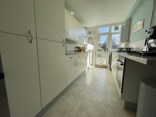 a kitchen with white cabinets and a large window at Harmonious Family Home in Westbury-on-Trym in Bristol