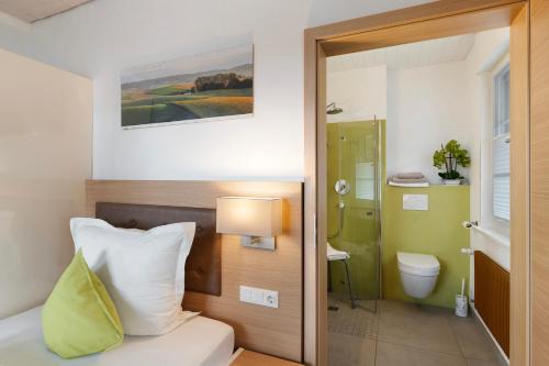 a bedroom with a bed and a bathroom with a toilet at Pension Waldliesel in Dornstetten