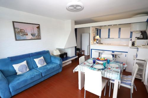 un salon avec un canapé bleu et une table dans l'établissement Magnifique vue mer Appart les pied dans l eau St Cyprien, à Saint-Cyprien