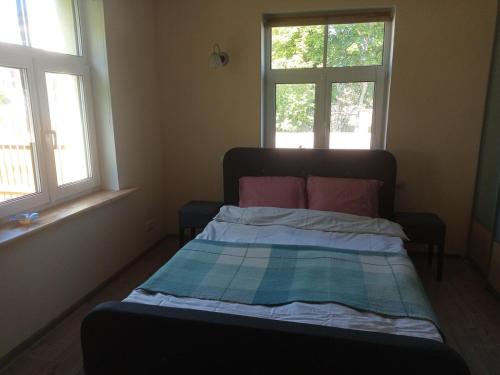 a bed in a small room with two windows at Apartment for 2 in the centre of town in Sigulda