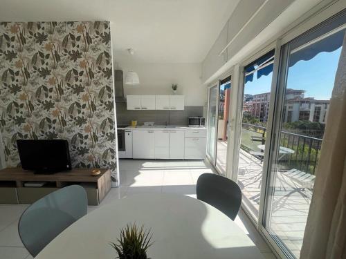 une cuisine avec une table et des chaises ainsi qu'une grande fenêtre dans l'établissement Scaliero T2 avec terrasse plein soleil, à Nice