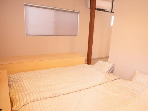 a bedroom with two beds and a window at Aso La Vista 阿蘇の家 in Aso