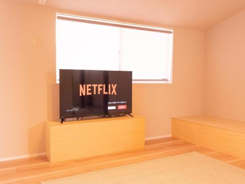 a flat screen tv sitting in a room with a window at Aso La Vista 阿蘇の家 in Aso