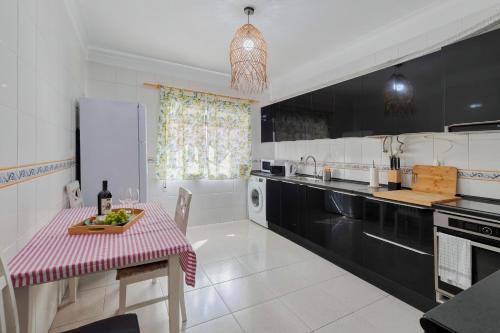 a kitchen with black and white appliances and a table at Lucia House - By Y Concept in Setúbal