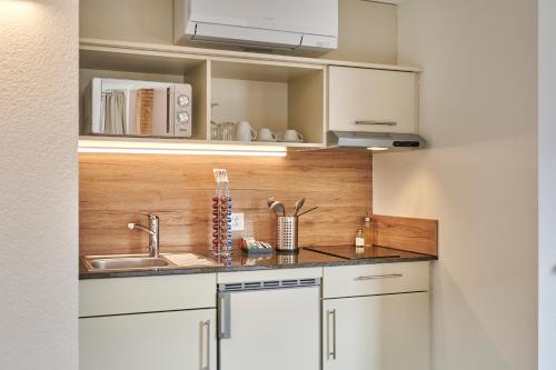 a kitchen with white cabinets and a sink at Aparthotel Krone - Self Check-In in Interlaken