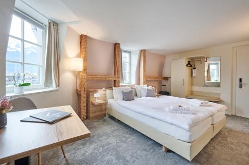 a bedroom with a large white bed and a table at Aparthotel Krone - Self Check-In in Interlaken
