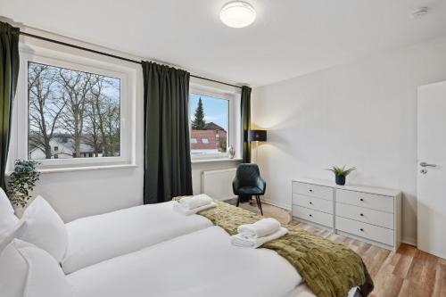 two beds in a room with a window at MAISUITES Sperling - Zentrale Ferienwohnung mit Boxspringbett, Kaffeevollautomat, WLAN & seitlichem Seeblick in Mölln
