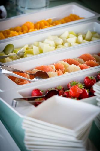 four white containers filled with different fruits and vegetables at Ghent River Hotel in Ghent
