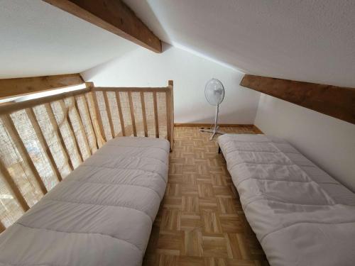 Cette chambre mansardée comprend deux lits et un ventilateur. dans l'établissement Maison de vacances, séjour cuisine, résidence MAS DE LA PLAGE 1, terrasse Sud dégagée 4 couchages Portiragnes LRMP77, à Portiragnes