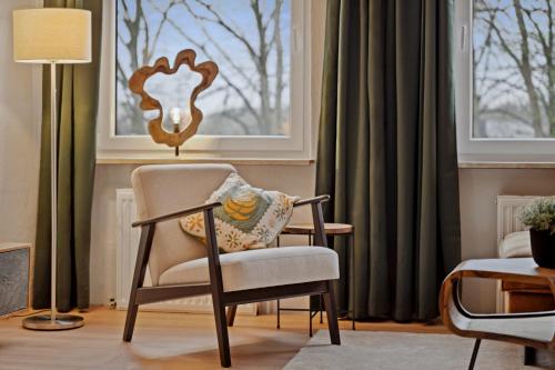 a living room with a chair and a window at MAISUITES Sperling - Zentrale Ferienwohnung mit Boxspringbett, Kaffeevollautomat, WLAN & seitlichem Seeblick in Mölln