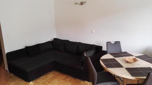 a living room with a black couch and a table at Apartment Šija in Bohinj