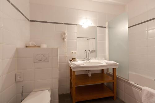 a white bathroom with a sink and a toilet at Ghent River Hotel in Ghent